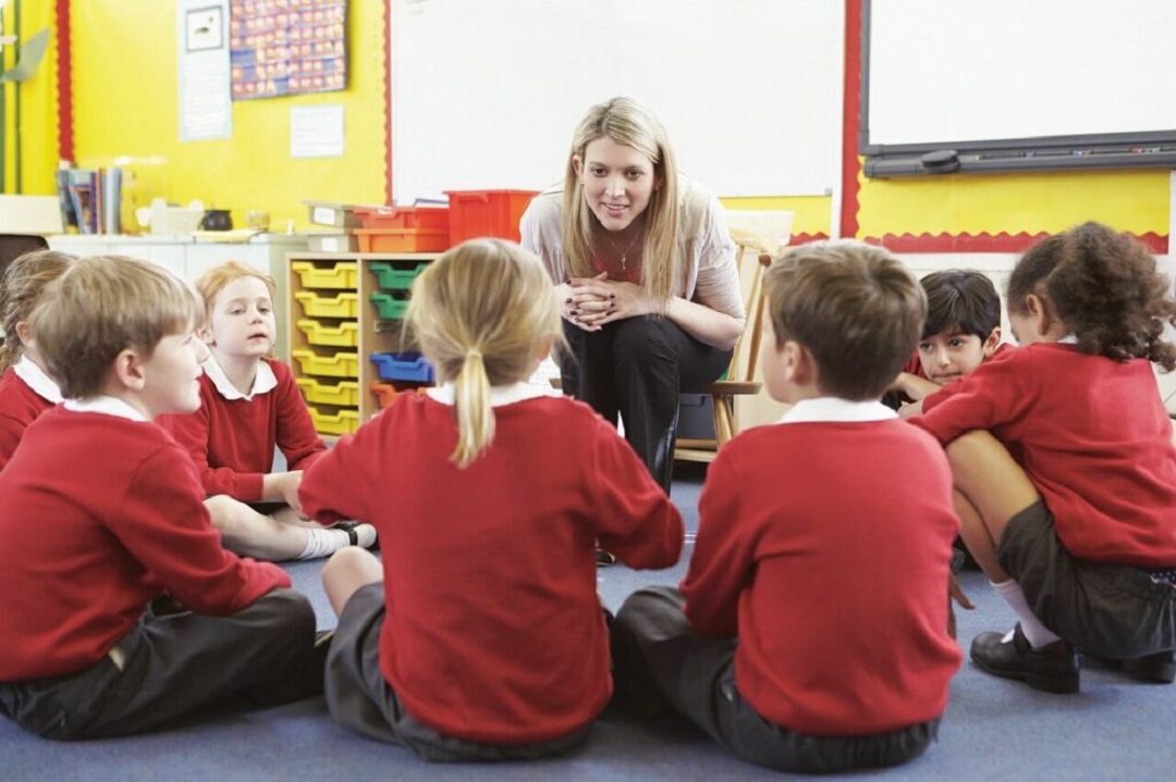 teacher sitting with her students