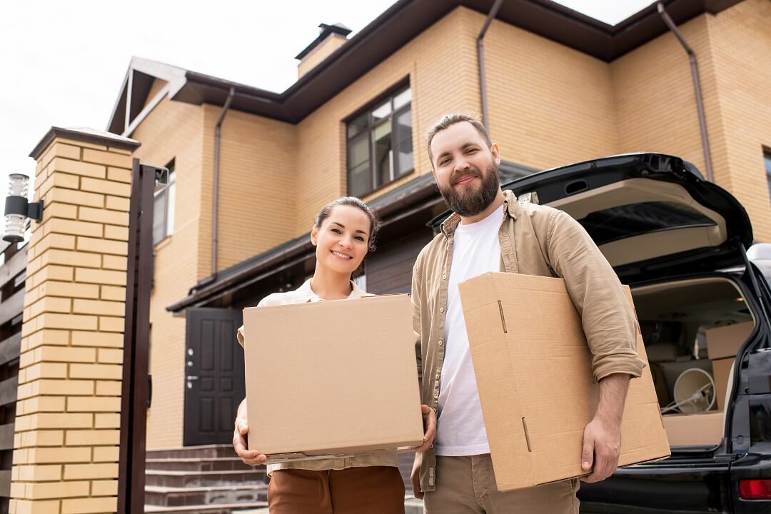 Couple carrying boxes moving to new home.