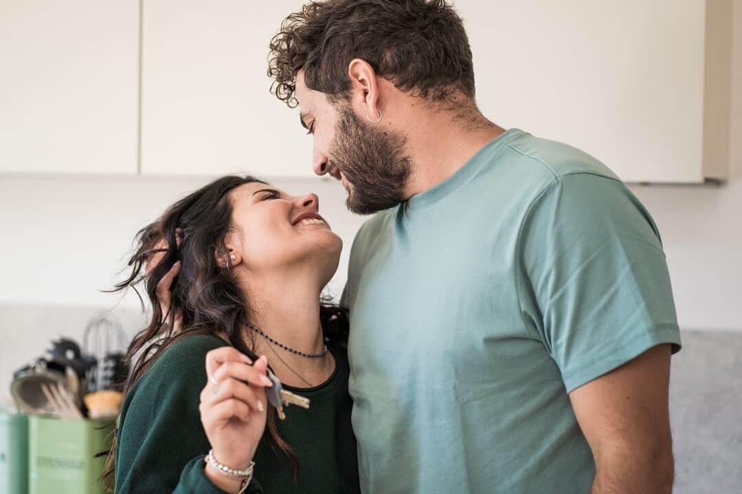 A young married couple holding a house key celebrating over the purchase of the new house