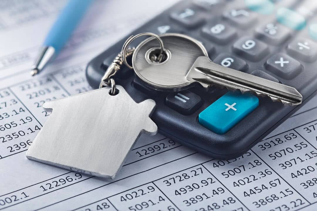 Home mortgage keychain with house symbol on a calculator and finance document