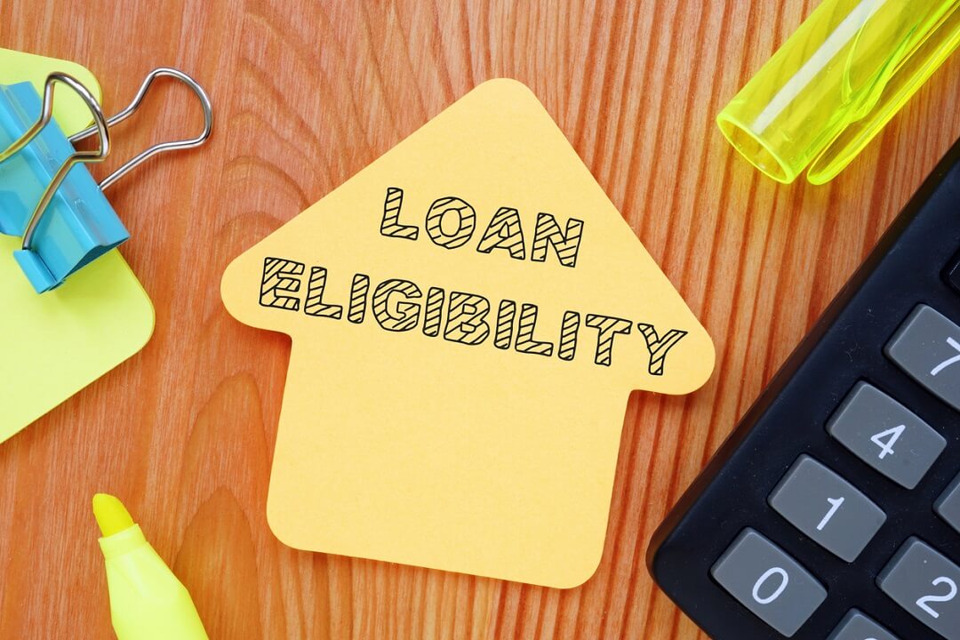 A house-shaped paper with the text 'loan eligibility' beside a calculator