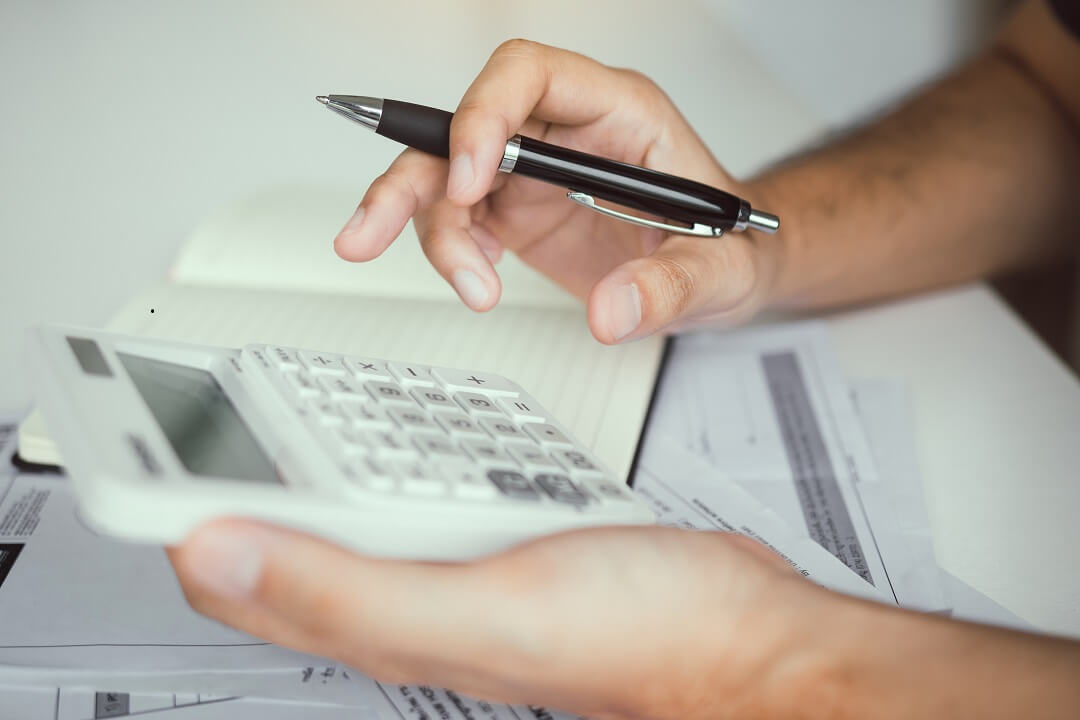 Man with calculator computing for closing costs and taxes.