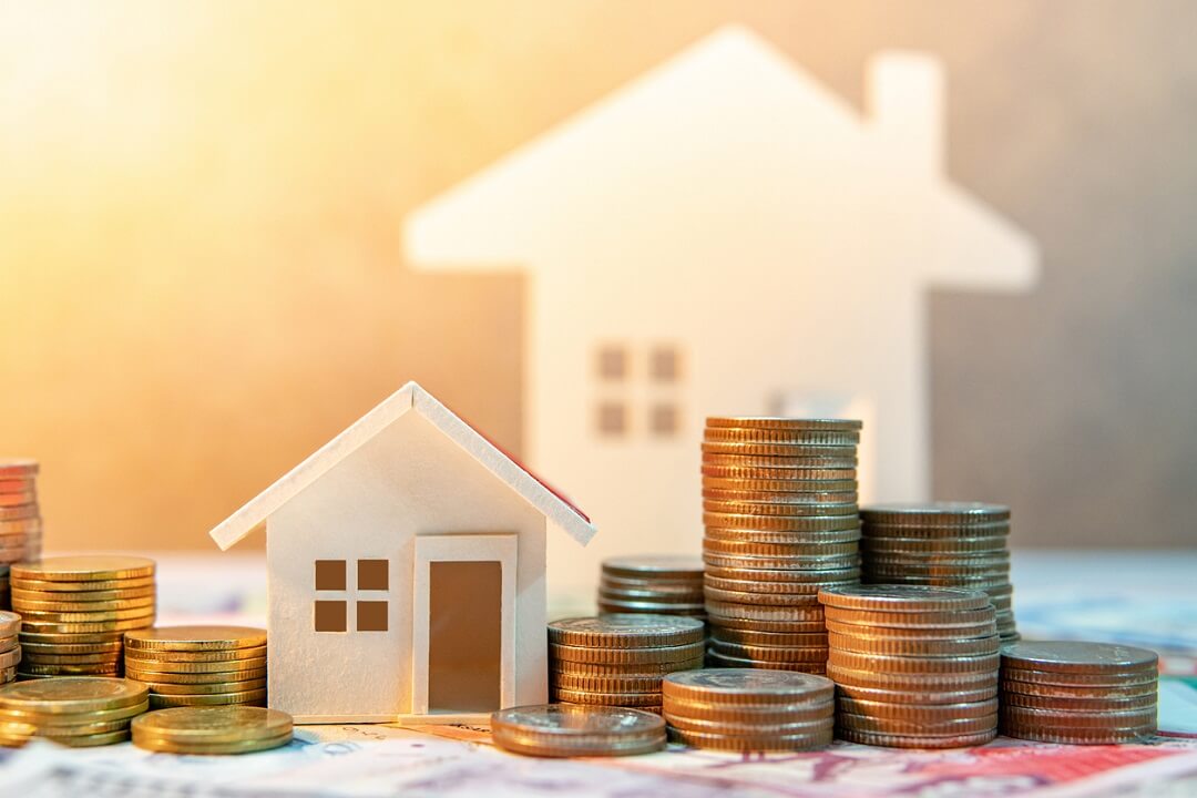 Model wooden house with coin stacks